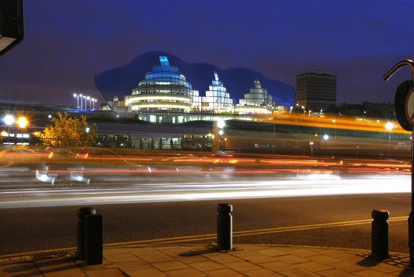 A vehicle drives by with the Sage Gateshead building featuring in the background